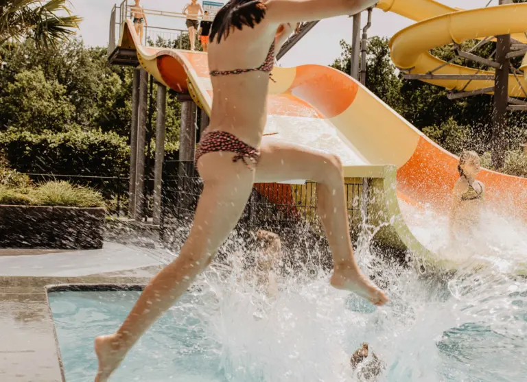 Camping de kleine wolf faciliteit zwembad meisje springt bij glijbaan